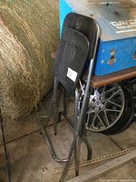 Side view of the black IKEA folding chair showing metal frame, padded backrest and seat, and footrest bar.