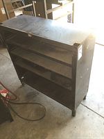 Front and side views of metal workshop shelf showing three shelves and surface rust.
