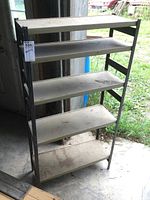 Front view of a four-shelf metal shelving unit showing overall condition and structure with dust on shelves.