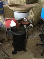 Full view of the black cylindrical oil drain tank with large white funnel top, wheeled base, and hose coiled on side handle