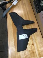 Full side view of the Sting Ray hydrofoil stabilizer fin showing shape, mounting holes, and surface texture on wooden table.