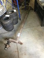 Full view of the torsion trailer axle showing the entire length of the metal axle on the floor.