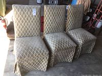 Three beige upholstered chairs in a garage setting, showing diamond patterned upholstery and pleated skirt.