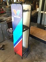 Front and side view of Valvoline branded metal display rack showing plastic signage panels and blue wire shelves.