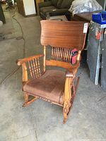 Front and side view of vintage wooden rocking chair showing tall backrest, spindle back and arms, and upholstered seat.