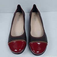 Top view of leather comfort shoes showing brown leather body, red patent toe cap and zipper detail.