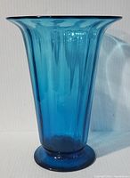 Full frontal image of ribbed aqua/turquoise blown glass vase showing shape and color.