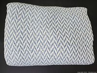 Folded cotton blanket showing blue and white woven herringbone pattern