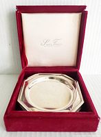 View of six stacked octagonal silver-plated coasters inside original velvet-lined box with lid open.