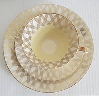Top view of the cup, saucer, and lunch plate stacked, showing the gold lattice trim design.