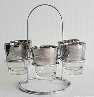 Set of five Queens Lusterware silver-toned shot glasses with etched floral designs in a chrome stand, full front view.