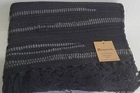 Folded hand woven Rivancia cotton rug black and grey with visible tag.