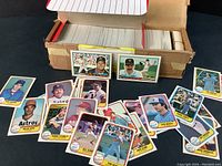 Photo shows an open box containing numerous 1981 Fleer baseball cards, with some cards laid out in front showing players like Nolan Ryan, Reggie Jackson, and others.