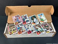 Multiple 1984 Topps baseball cards laid out inside original box, showing players from teams like Phillies, Astros, Red Sox, Orioles, Angels, Yankees, and Athletics.