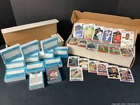 Two boxes of 1988 baseball cards displayed. One box contains blue sealed Donruss Diamond Kings card sets with backs showing detailed player statistics and puzzle pieces included. The other is an open Fleer card box with loose cards and stickers.