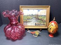Overall lot of four items showing the Fenton cranberry glass vase, Italian landscape painting, Russian icon egg, and glass bird figurine grouped together.