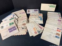 Photo shows multiple stacks of first day covers with a wide variety of cancelled stamps, some addressed to recipients, including airmail envelopes.