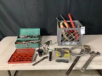 Full view of the hand tools set on table showing all items including tools in two plastic crates, wrenches, glue gun, and small parts organizer tray.