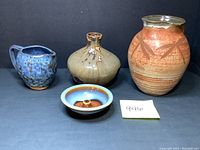 All four pottery pieces together showing scale and glaze colors - blue and brown glazes visible
