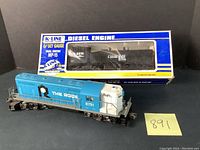 K-Line MP-15 Norfolk Southern diesel engine numbered 2215 in original packaging and Lionel The Rock diesel engine numbered 8751 outside box, showing paint and condition.