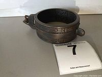 Front angle view of the brass sundial ring showing inscribed markings and attached loop.