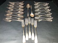 All flatware pieces arranged on black background: forks and spoons