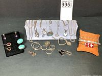 Overview showing necklaces on display stand, bracelets on cushion, rings and earrings in foreground