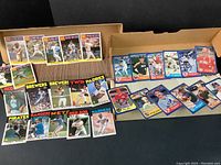 Wide shot of two cardboard boxes filled with loose 1986 Topps and Fleer baseball cards, including visible player cards and '85 Beyond Breaker' inserts.