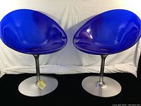 Two blue polycarbonate swivel chairs on aluminum pedestal bases side by side