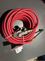 Coiled red air hose with metal fittings, secured with zip tie and original product tag visible.