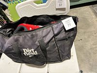 Carrying bag with Dirt Devil logo and visible zipper, holding vacuum and attachments