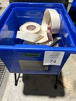 Blue bin containing drywall tape rolls and drywall putty knives, showing general contents and condition