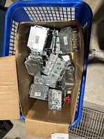 Metal electrical boxes and covers inside a cardboard box in blue basket