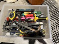 First photo shows a plastic bin filled with various hand tools including measuring tape, hammer, screwdrivers, clamps, and a level.