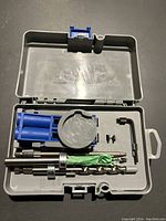 Open gray plastic carrying case containing a Kreg pocket hole jig and accessories including drill bits, stop collar, screws, and a hex wrench.