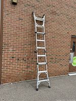 Full view of the aluminum ladder extended as a straight ladder leaning on brick wall.