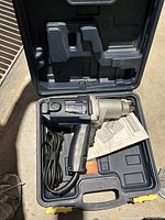 Open carrying case showing the Mastercraft electric impact wrench with power cord and instruction manual inside