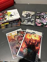 Photo showing a stack of comic books with visible titles including Spawn, Watchmen, Moon Knight, Daredevil, and Preacher, alongside copies of Dark Souls, Judge Dredd, and Spawn comics fanned out in front.