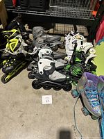 Photo showing multiple pairs of roller blades and roller skates of various colors and styles on floor