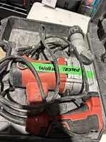 Hammer drill inside case with power cord with work tested tape.