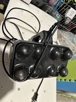 Side view of black Thumper Max I Pro handheld electric massager showing eight rounded massaging nodes and cord.