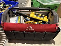 Front view of Husky tool box with hand saw, DeWalt tape measure, spirit level, and other tools inside