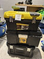 Stacked view of three tool storage bins including Stanley, DeWalt, and Husky brands showing overall condition and size relationship.