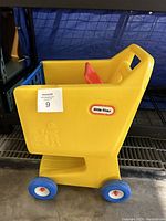Side view of the vintage yellow Little Tikes toy shopping cart showing brand logo and embossed child figure with shopping cart detail on side panel.