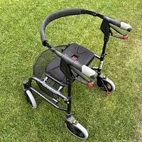 Heavy Duty Nexus walker rollator shown from a front angled top view on grass, showing padded seat, mesh basket, handlebar with brakes.