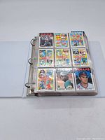 White binder open showing one page of nine cards, including Reds, Angels and Indians cards