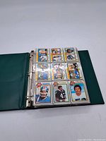 Open binder showing one page of nine vintage Topps football cards