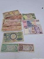 Image showing assorted vintage and used world paper currency in various denominations and countries, laid out on a flat surface.