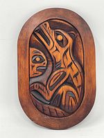 Image of oval vertical carved wooden Haida plaque with animal motif in relief carving