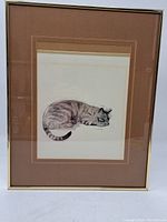 Full view of the framed wall art showing the sleeping cat illustration, brown matting, and thin gold frame.